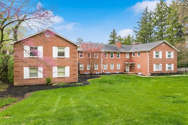 rear view of house featuring a yard and brick siding