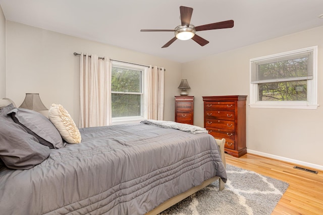 bedroom with visible vents, baseboards, a ceiling fan, and wood finished floors