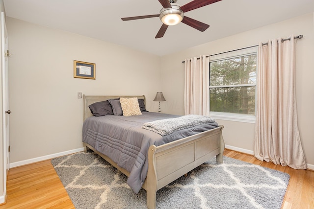 bedroom with light wood-style flooring, ceiling fan, and baseboards