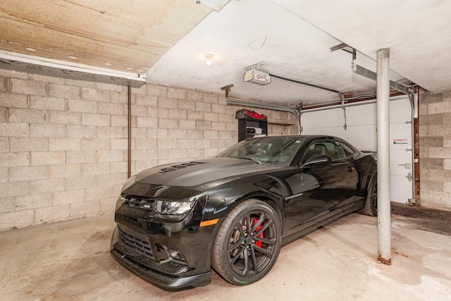 garage with a garage door opener and concrete block wall