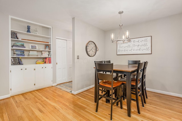 dining space with light wood-style flooring, baseboards, and an inviting chandelier