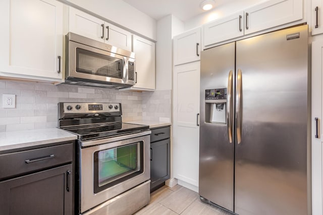 kitchen with decorative backsplash, white cabinetry, and stainless steel appliances