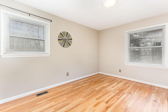 unfurnished room with visible vents, baseboards, and wood finished floors