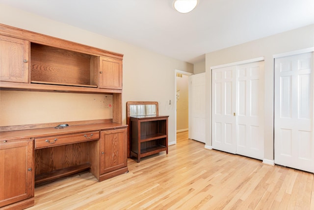 unfurnished office with baseboards and light wood-style floors