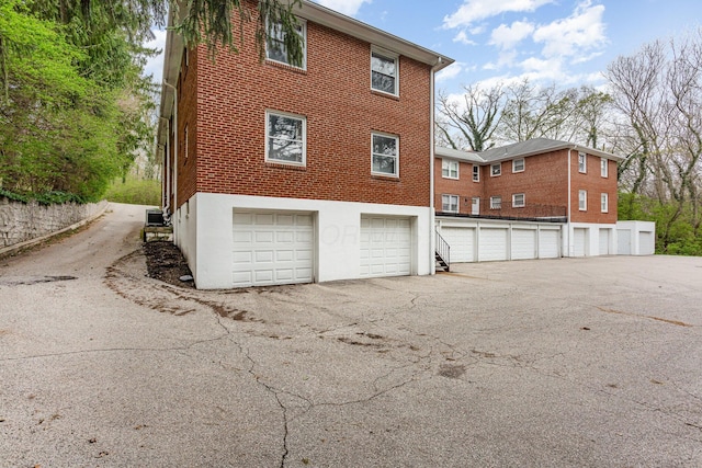 view of home's exterior featuring community garages, central AC unit, and brick siding