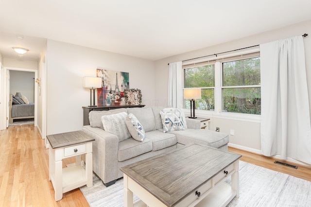 living room with light wood-style floors, baseboards, and visible vents