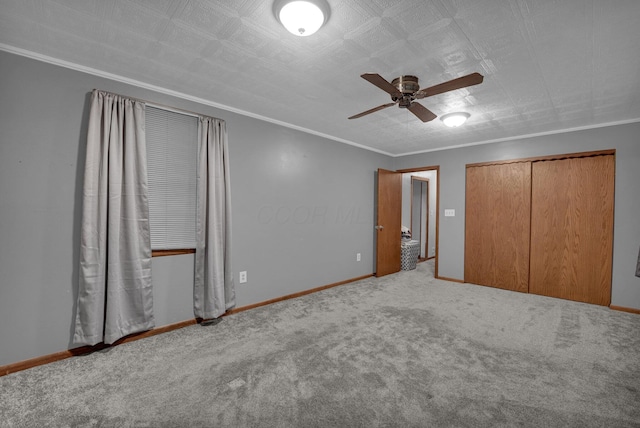 unfurnished bedroom with ornamental molding, carpet flooring, ceiling fan, and a closet