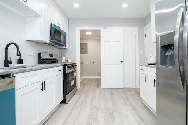 kitchen featuring light stone counters, appliances with stainless steel finishes, light hardwood / wood-style flooring, and white cabinets