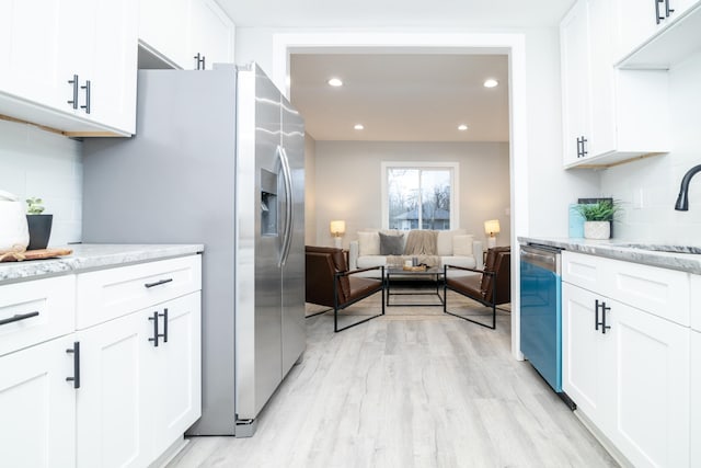 kitchen with light stone counters, stainless steel appliances, sink, and white cabinets