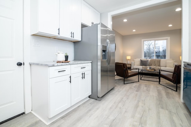 kitchen with light hardwood / wood-style flooring, white cabinets, and stainless steel fridge with ice dispenser