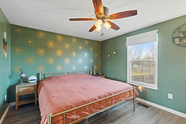 bedroom with hardwood / wood-style flooring, ceiling fan, and a textured ceiling