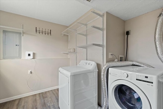 clothes washing area featuring separate washer and dryer, hardwood / wood-style floors, electric panel, and a textured ceiling