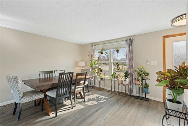 dining area featuring dark wood-type flooring and a textured ceiling