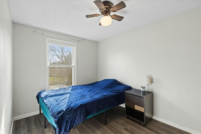 bedroom with ceiling fan, dark wood-type flooring, and a textured ceiling