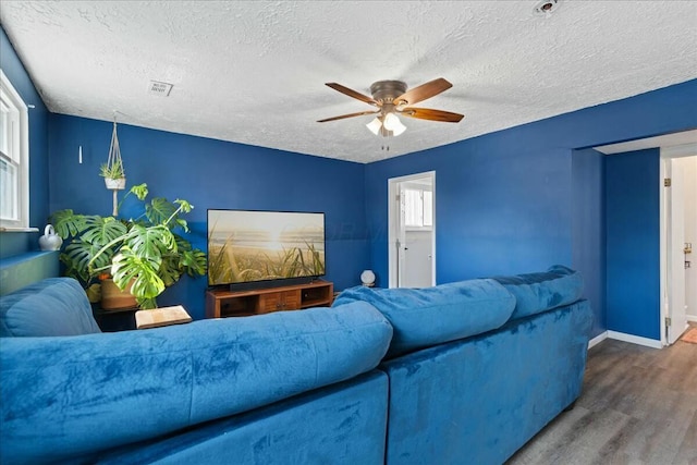 living room with dark hardwood / wood-style floors, a textured ceiling, and ceiling fan