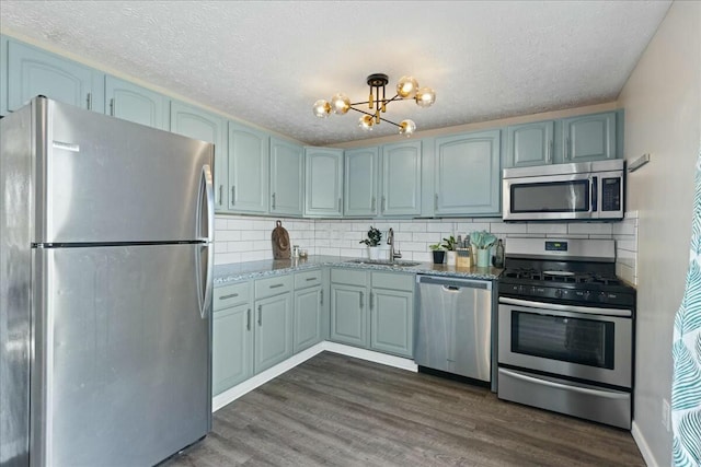 kitchen featuring sink, a notable chandelier, dark wood-type flooring, and appliances with stainless steel finishes