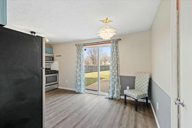 interior space featuring hardwood / wood-style floors, a textured ceiling, and appliances with stainless steel finishes