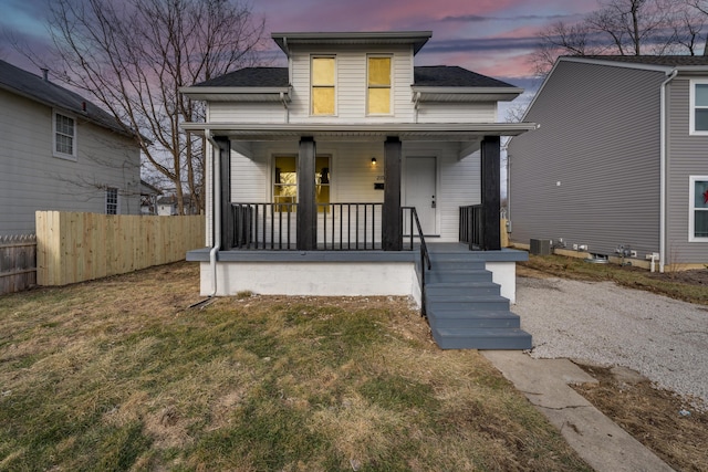 view of front of home with central AC unit, a yard, and covered porch