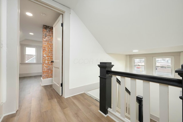 hallway featuring lofted ceiling, light hardwood / wood-style floors, and a wealth of natural light