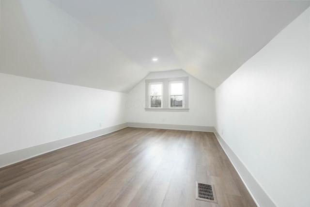 additional living space with vaulted ceiling and light wood-type flooring