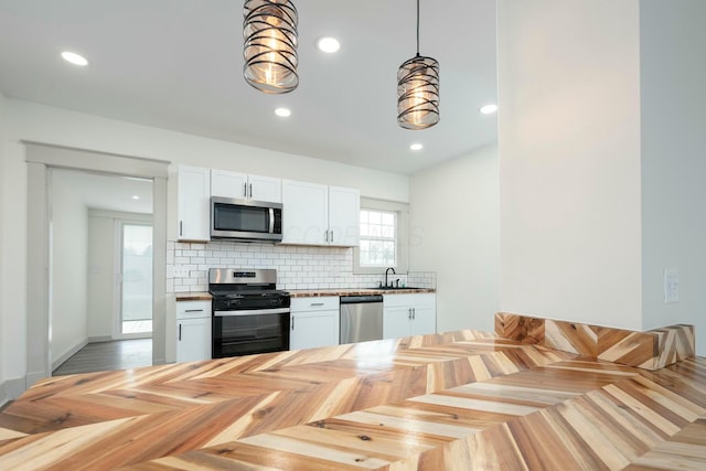 kitchen with hanging light fixtures, white cabinetry, appliances with stainless steel finishes, and sink