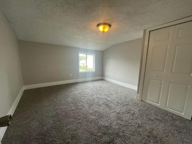 unfurnished room featuring carpet, lofted ceiling, and a textured ceiling