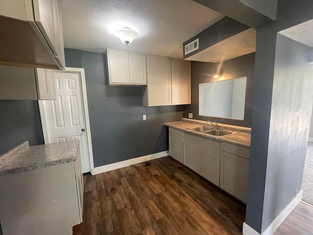 kitchen with white cabinetry, dark hardwood / wood-style flooring, sink, and a textured ceiling