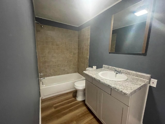 full bathroom with hardwood / wood-style flooring, tiled shower / bath, vanity, and toilet