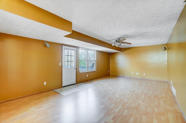 empty room with ceiling fan, light hardwood / wood-style flooring, and a textured ceiling