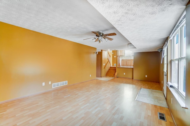 unfurnished living room with ceiling fan, light hardwood / wood-style floors, and a textured ceiling