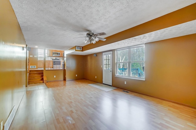 interior space with a healthy amount of sunlight, a textured ceiling, and light wood-type flooring