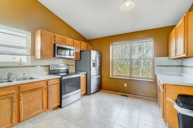 kitchen with sink, light tile patterned floors, stainless steel appliances, decorative backsplash, and vaulted ceiling