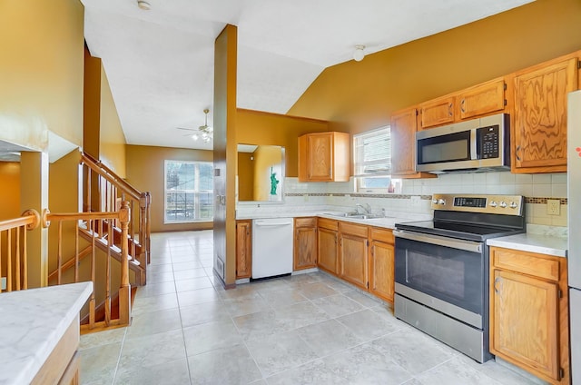 kitchen with appliances with stainless steel finishes, lofted ceiling, sink, decorative backsplash, and ceiling fan