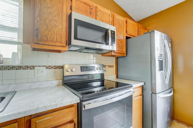 kitchen with tasteful backsplash, vaulted ceiling, a textured ceiling, and appliances with stainless steel finishes