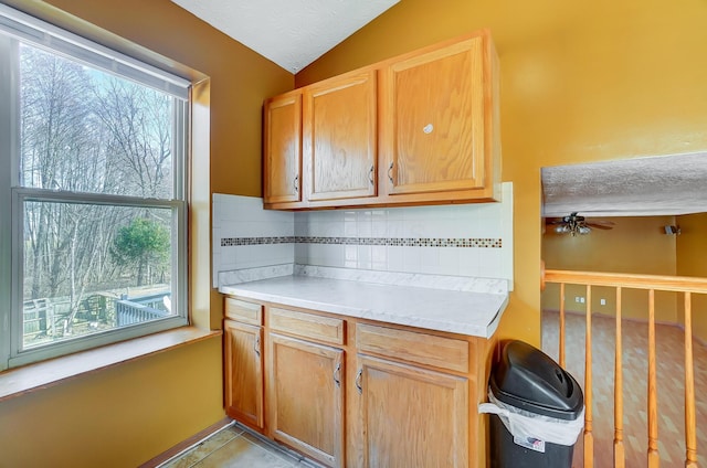 kitchen with vaulted ceiling, a textured ceiling, light tile patterned floors, ceiling fan, and decorative backsplash