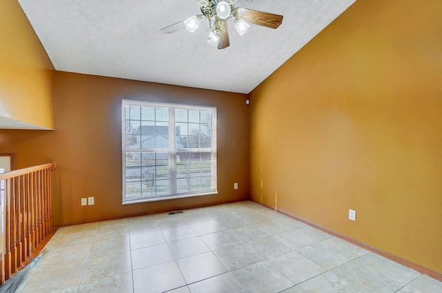 tiled empty room with ceiling fan and a textured ceiling