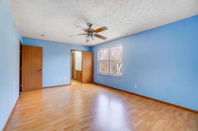 unfurnished bedroom featuring ceiling fan, connected bathroom, a textured ceiling, and light wood-type flooring