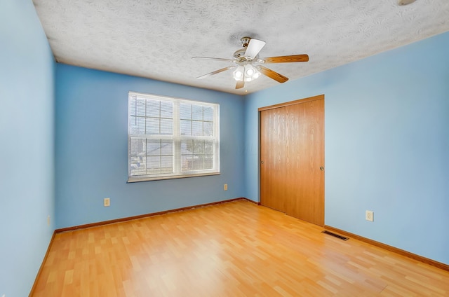 empty room with ceiling fan, hardwood / wood-style flooring, and a textured ceiling