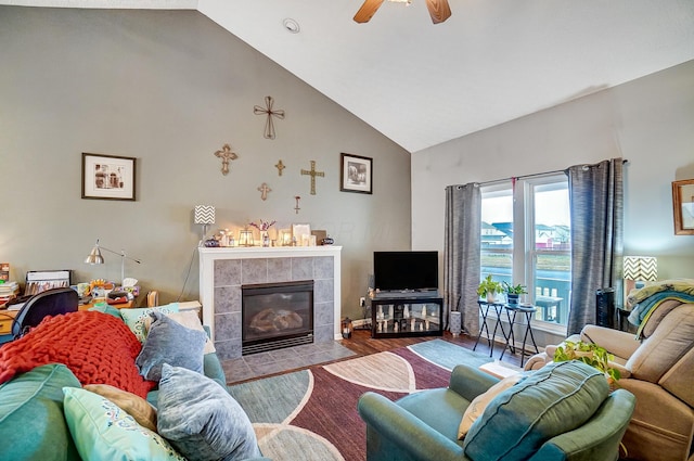 living room with ceiling fan, high vaulted ceiling, a tile fireplace, and light wood-type flooring