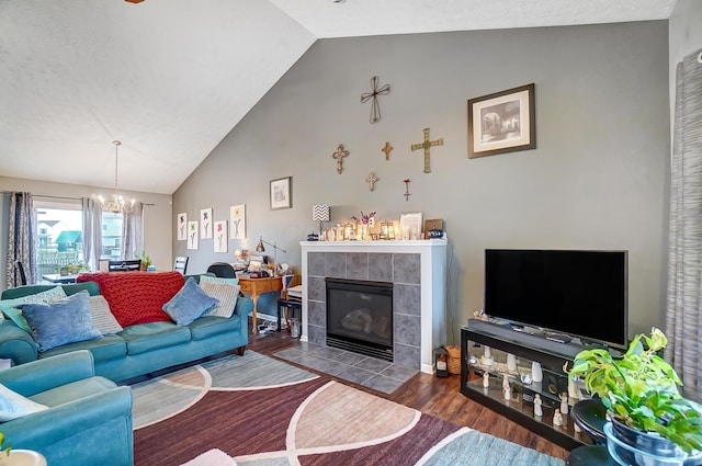 living room with a tiled fireplace, vaulted ceiling, hardwood / wood-style floors, and a chandelier