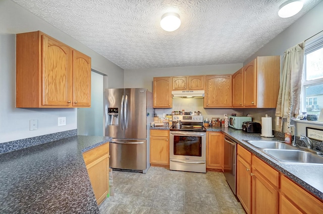 kitchen with appliances with stainless steel finishes, sink, and a textured ceiling