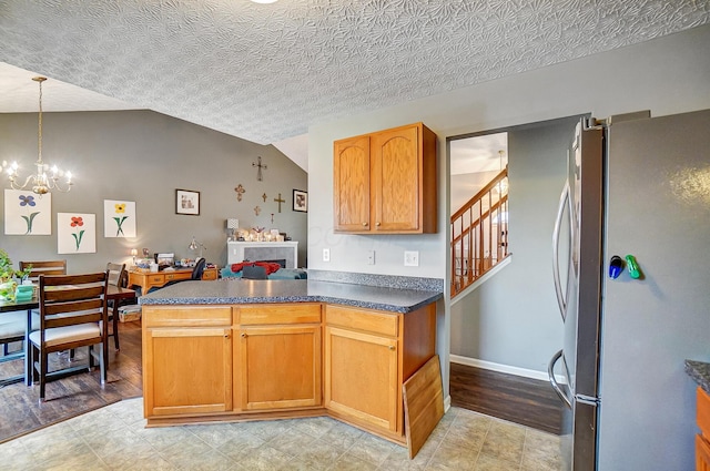 kitchen with lofted ceiling, a chandelier, hanging light fixtures, a textured ceiling, and stainless steel fridge