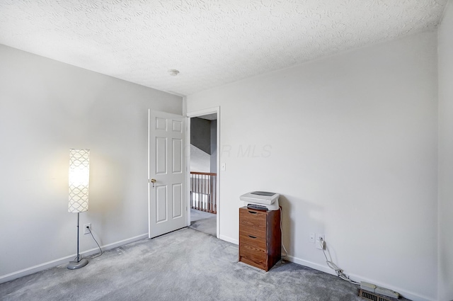 spare room featuring light carpet and a textured ceiling