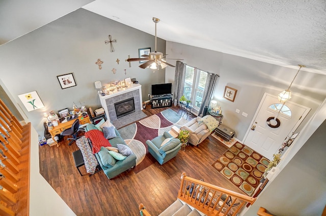 living room with a tiled fireplace, ceiling fan, hardwood / wood-style flooring, and a textured ceiling