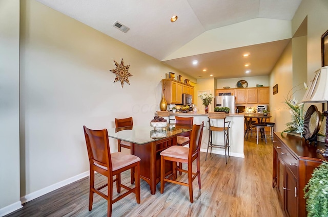 dining room with lofted ceiling and light hardwood / wood-style flooring