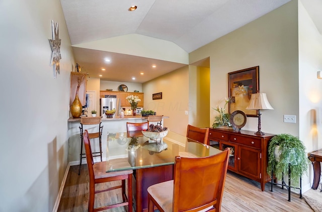 dining area featuring lofted ceiling and light wood-type flooring