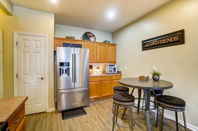 kitchen featuring high end fridge and light wood-type flooring