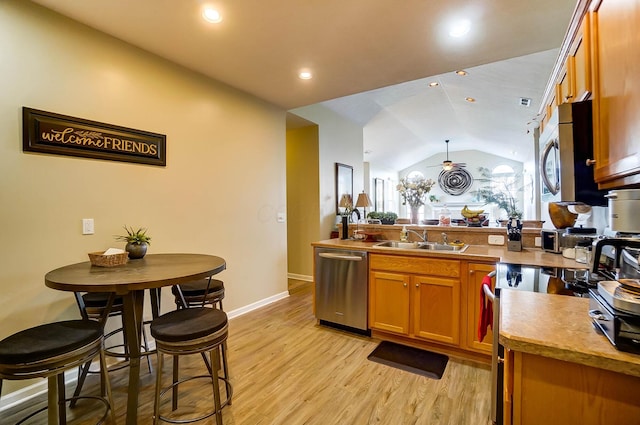 kitchen featuring lofted ceiling, sink, light wood-type flooring, appliances with stainless steel finishes, and kitchen peninsula