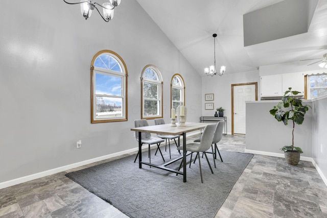 dining space with ceiling fan with notable chandelier and high vaulted ceiling