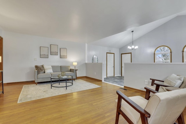 living room with high vaulted ceiling, a notable chandelier, and light wood-type flooring